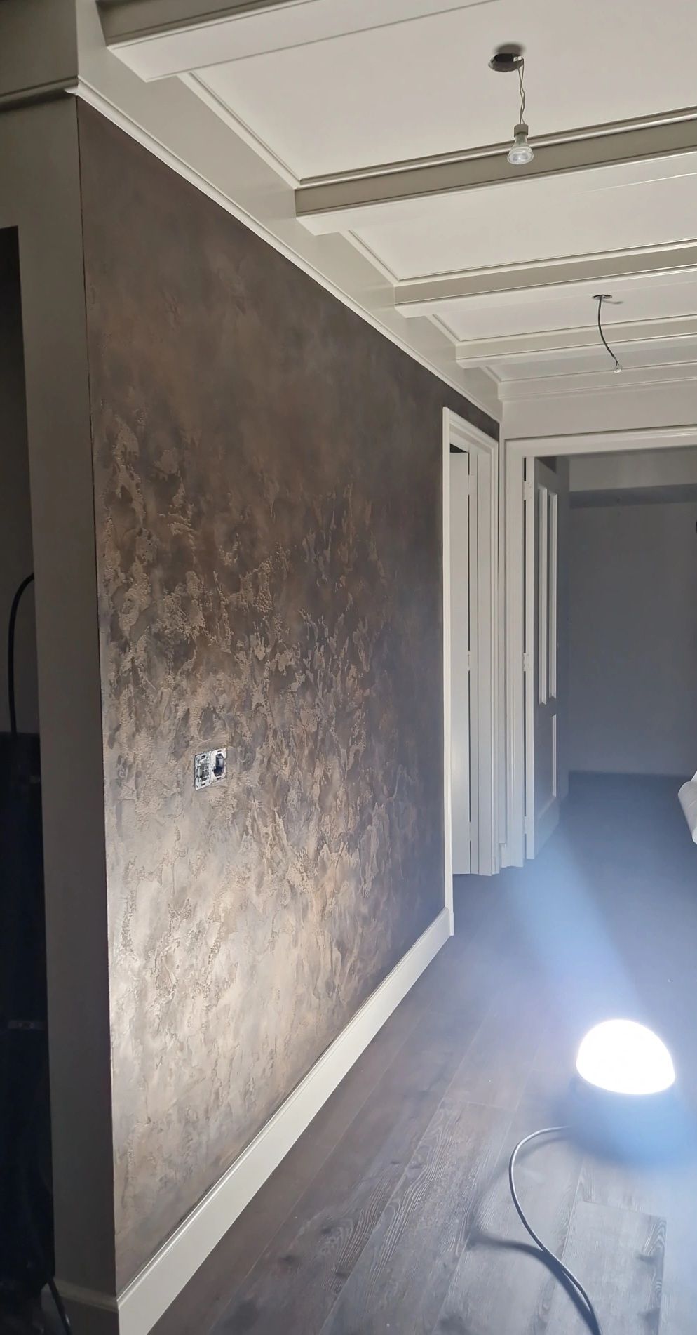 Wand in een gang, afgewerkt in brons met een metallic reliëf